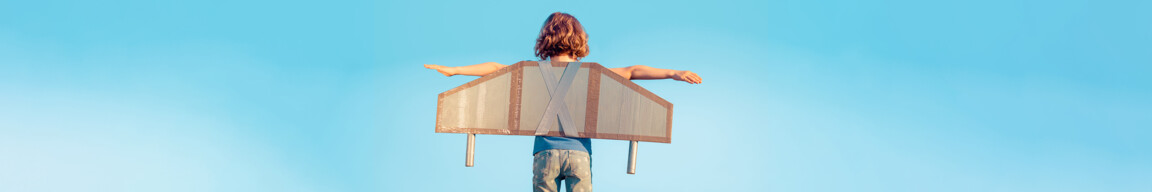 Kind mit gebastelten Flügeln spielt Flugzeug